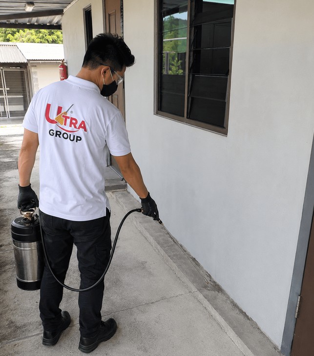 Pest Care technician treating building exterior